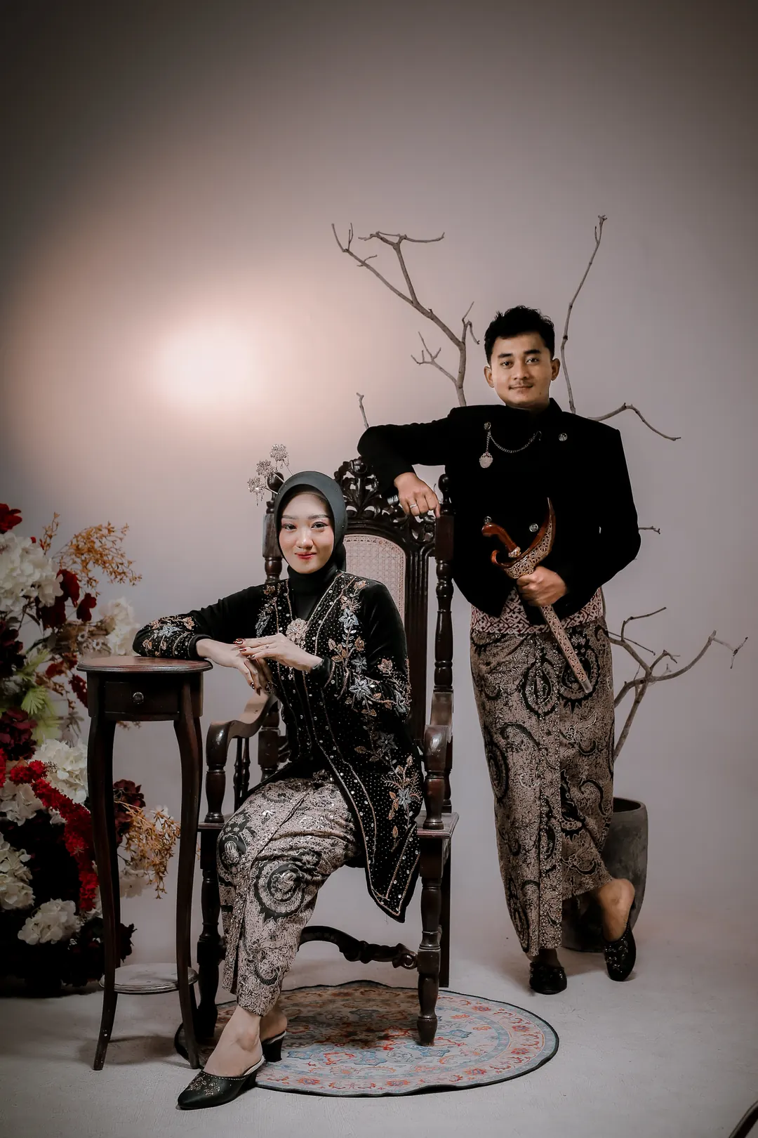 Nadea duduk di kursi ukir, Adit berdiri memegang keris